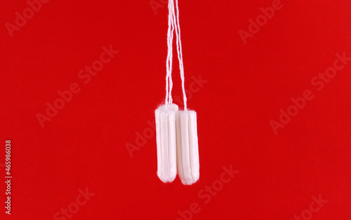 White hygiene tampons on a string on a red background