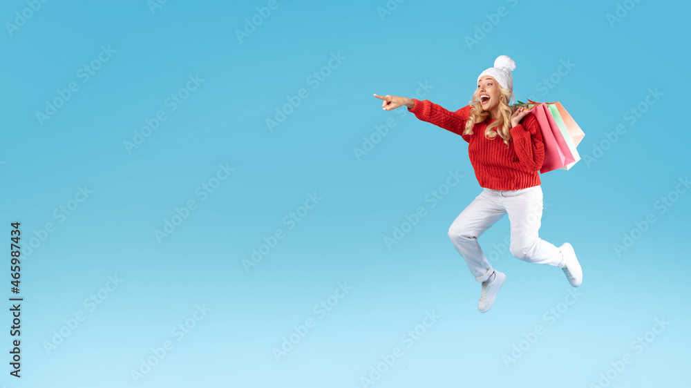 Excited blonde woman jumping with shopping bags at studio Excited blonde woman jumping with shopping bags at studio