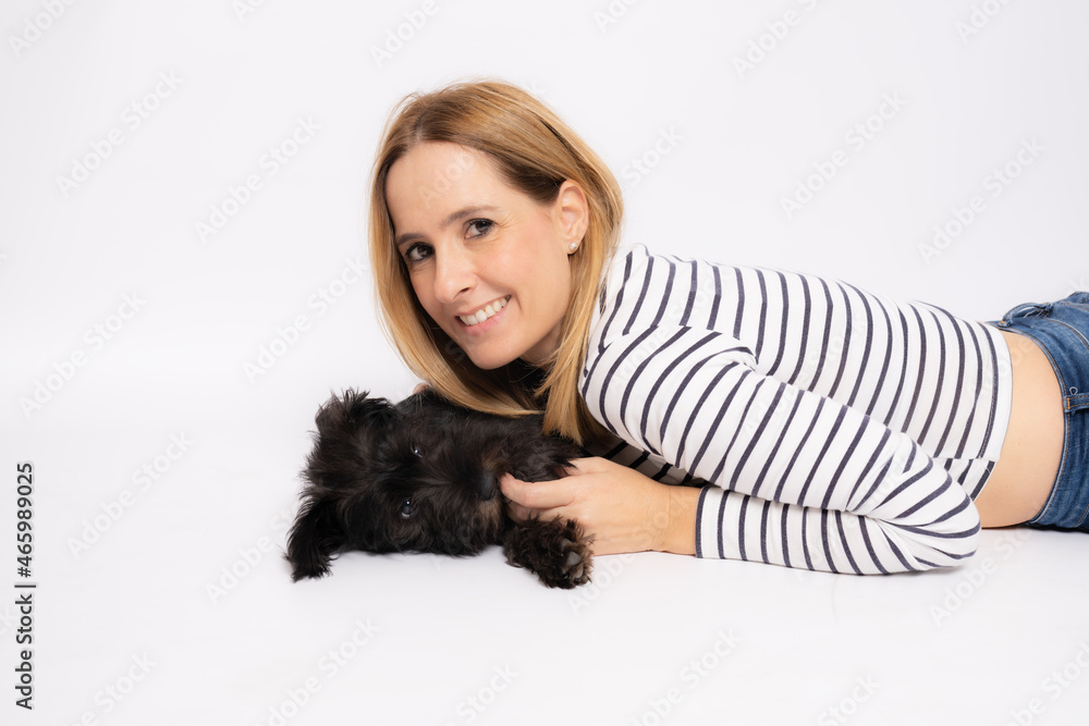 Young smiling woman lying on the floor embracing her dog isolated over white background. Young smiling woman lying on the floor embracing her dog isolated over white background.