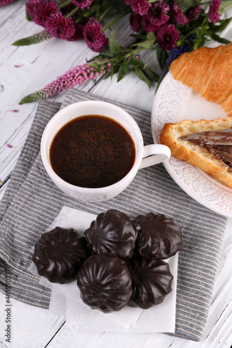 Marshmallow in chocolate, croissant and black coffee with cinnamon on a white wooden background