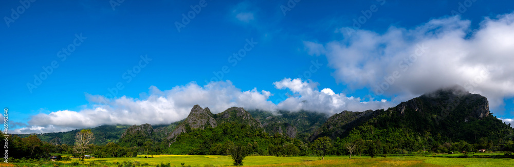 Panorama Mountain  Blue sky with white clouds.landscape with blue sky. White clouds and bright sun in blue sky. Green fields under blue sky on a sunny day. Beautiful spring background.