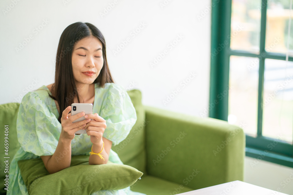 Beautiful happy women sitting on green couch use smartphone Beautiful happy women sitting on green couch use smartphone