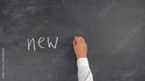 A man's hand writes the phrase NEW SKILLS on a chalkboard