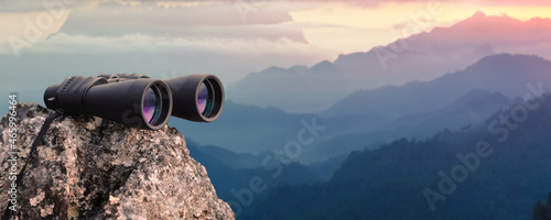 Binocular on top of rock mountain at sunset photo