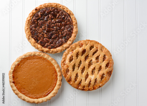 Three pies, Apple, Pumpkin, and Pecan. Pies are favorite desserts for the American Holidays, Thanksgiving and Christmas. Horizontal high angle shot with copy space.