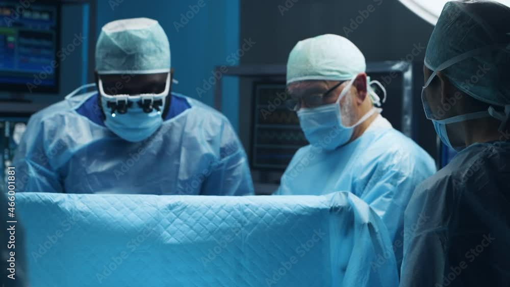 Multiracial team of professional medical surgeons performs the surgical operation in a modern hospital. Doctors are working to save the patient. Medicine, health and neurosurgery. Multiracial team of professional medical surgeons performs the surgical operation in a modern hospital. Doctors are working to save the patient. Medicine, health and neurosurgery.