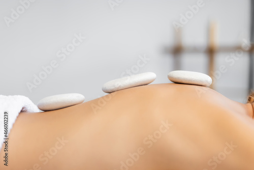 cropped view of woman receiving hot stone massage in spa center