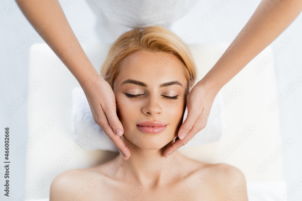 top view of masseur doing face massage of blonde client top view of masseur doing face massage of blonde client