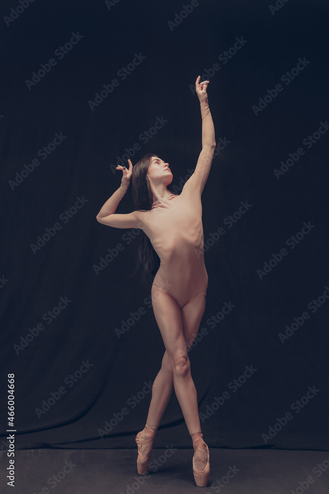 Naklejka premium Young flexible dancer, beautiful graceful woman in modern art performance isolated on black studio background. Art, motion, inspiration concept.