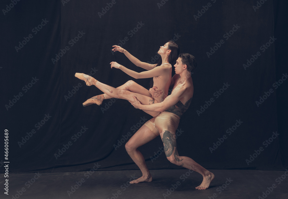 Two flexible dancer, young man and woman in modern art performance isolated on black studio background. Art, motion, inspiration concept.