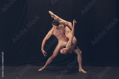 Fototapeta Naklejka Na Ścianę i Meble -  Two flexible dancer, young man and woman in modern art performance isolated on black studio background. Art, motion, inspiration concept.