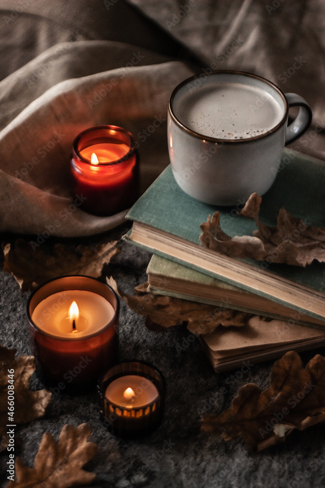 old books, coffee cup and burning candles with dry oak leaves on a stone background old books, coffee cup and burning candles with dry oak leaves on a stone background