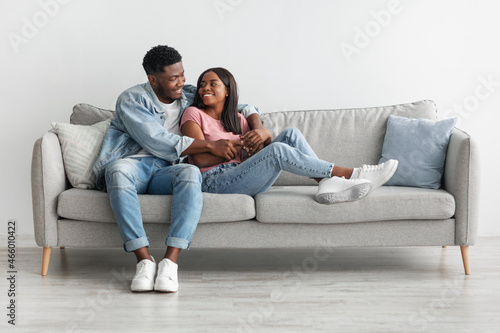 African american couple spending weekend together sitting on couch