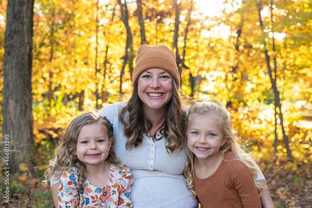 Fototapeta premium Cute young mom and two little girls in autumn at golden hour