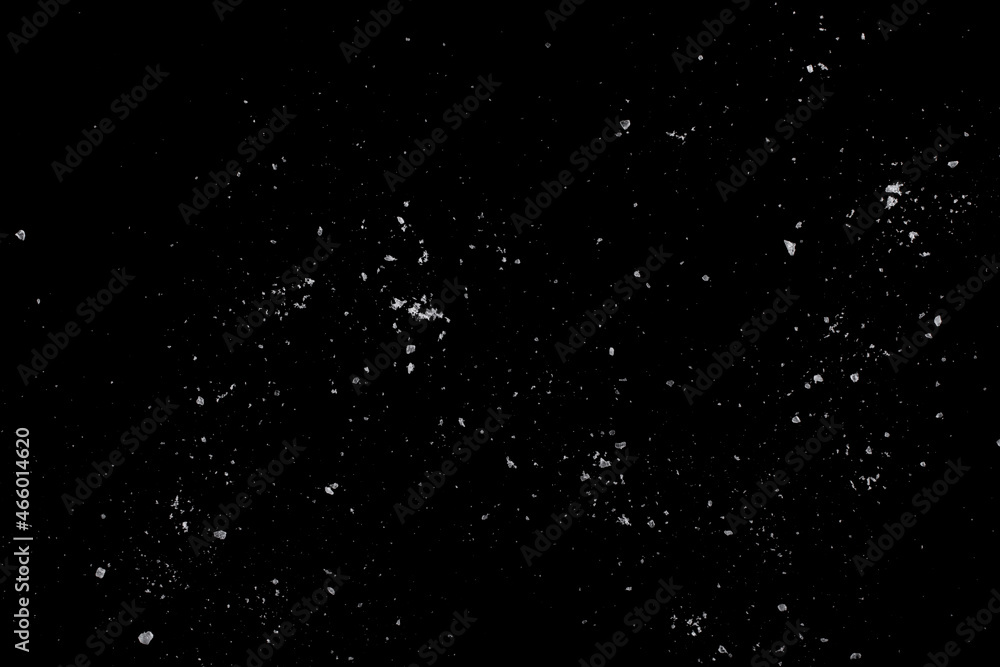 White crystals of salt on a black surface.