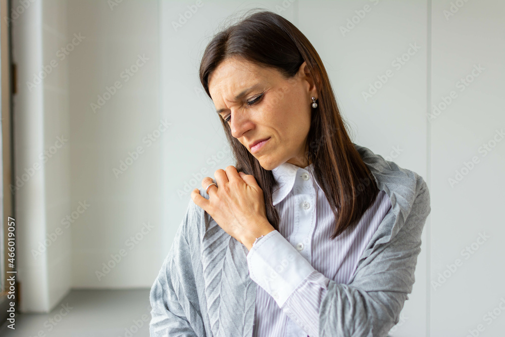 Close-up portrait of tired female massaging her neck. Moody beautiful woman holding her neck. Tired woman having pan in neck.Healthy lifestyle. Back and spine disease. Close-up portrait of tired female massaging her neck. Moody beautiful woman holding her neck. Tired woman having pan in neck.Healthy lifestyle. Back and spine disease.
