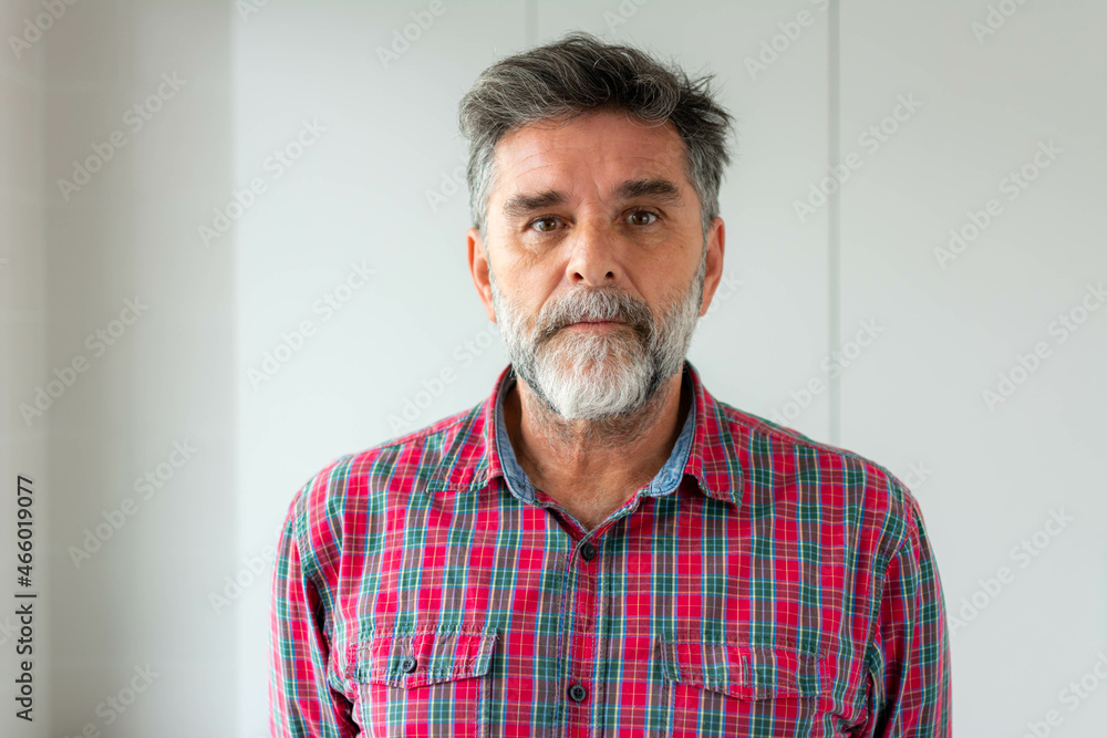 Obraz premium Isolated shot of senior handsome male with beard, mustache, trendy and hairdo. Relaxed with serious expression on face. Simple and natural looking at the camera.