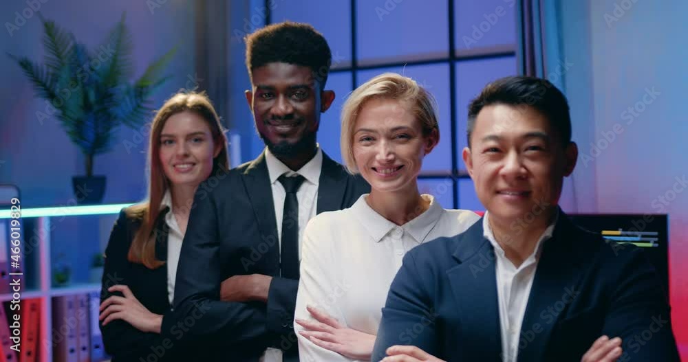 Attractive smiling happy confident experienced diverse businesspeople posing on camera with crossed arms on workroom with night lightings background,front view Attractive smiling happy confident experienced diverse businesspeople posing on camera with crossed arms on workroom with night lightings background,front view