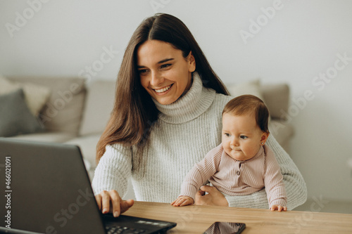 Mother with baby daughter working on computer from home