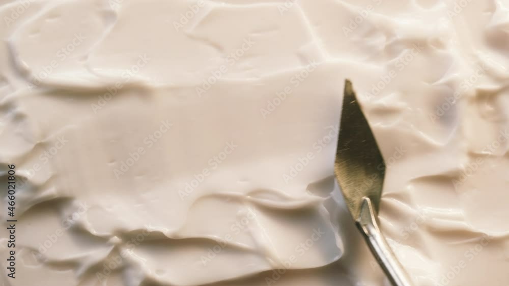 Smearing cream on white background, using spatula. Moisturizing balm texture close-up. Makeup and beauty products concept, cosmetics. Smearing cream on white background, using spatula. Moisturizing balm texture close-up. Makeup and beauty products concept, cosmetics.
