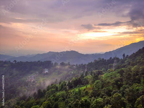 dramatic sunset orange sky over mountain range and green forest at evening from hill top © explorewithinfo