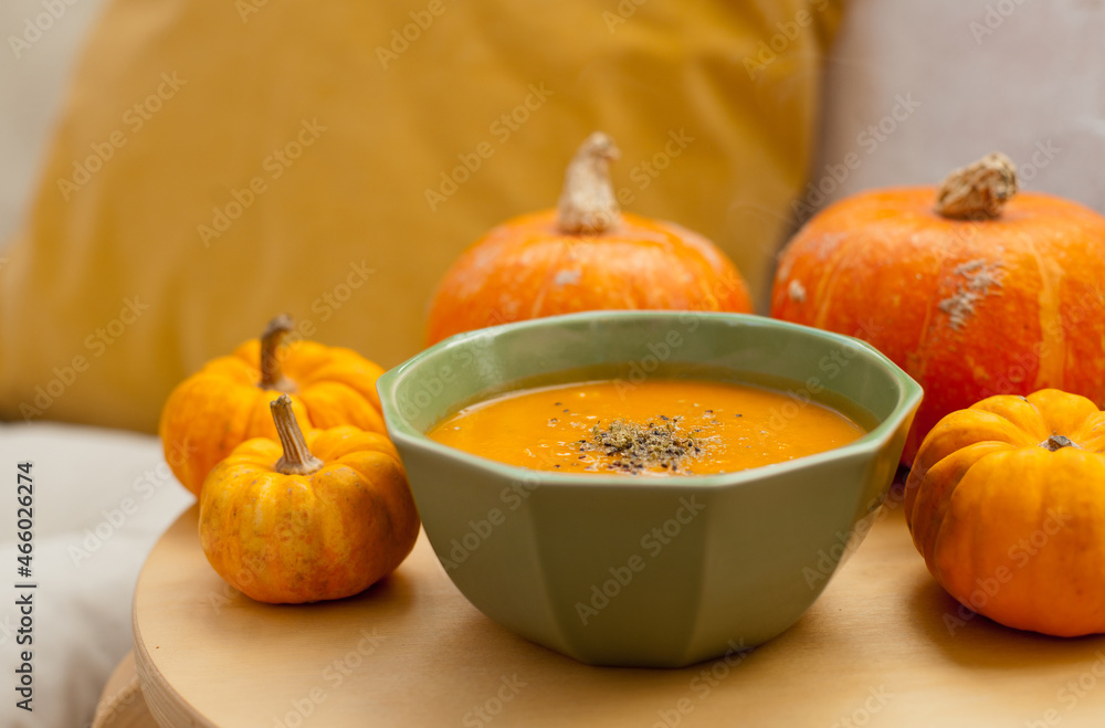pumpkin soup in a bowl with pumpkins around it