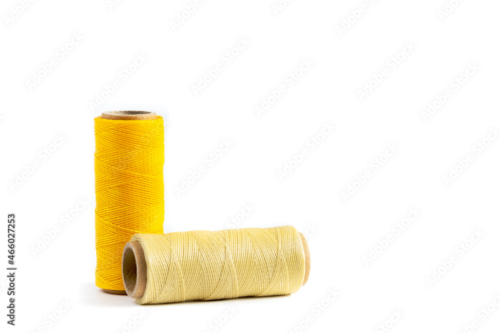 A skein of yellow and beige thread. Coils of colored threads on a white background. Waxed sewing thread for leather goods. A skein of yellow and beige thread. Coils of colored threads on a white background. Waxed sewing thread for leather goods.