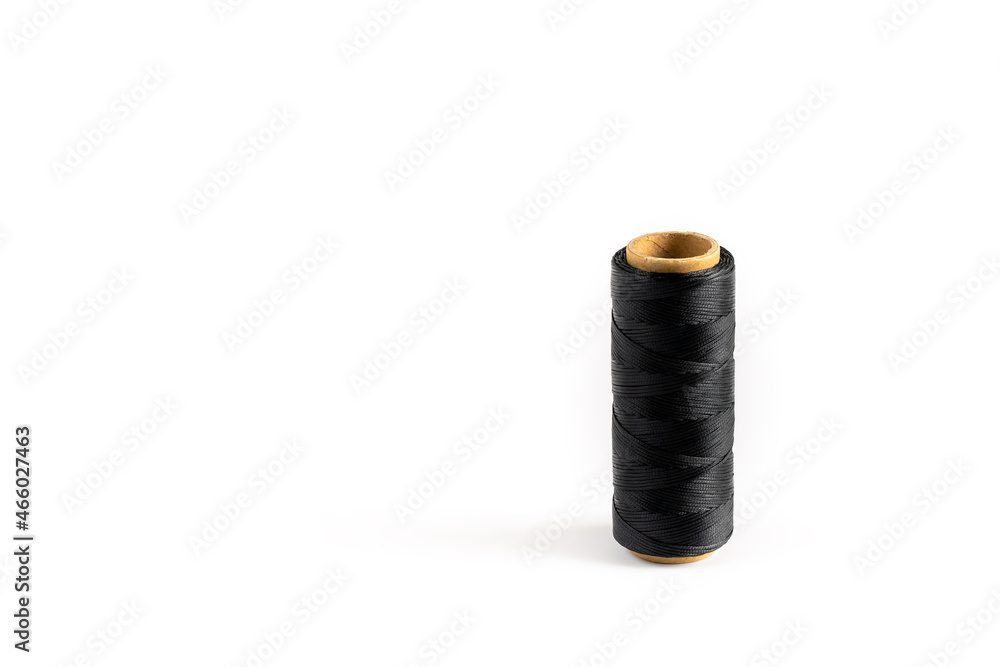 A coil of black thread. Spool of colored threads on a white background. Waxed sewing thread for leather crafts. A coil of black thread. Spool of colored threads on a white background. Waxed sewing thread for leather crafts.