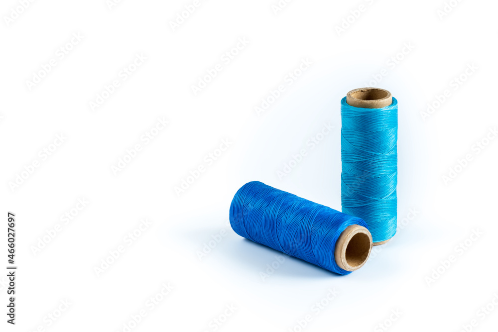 A skein of cyan and blue thread. Coils of colored threads on a white background. Waxed sewing thread for leather goods. A skein of cyan and blue thread. Coils of colored threads on a white background. Waxed sewing thread for leather goods.