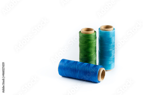A skein of green, blue and cyan thread. Coils of colored threads on a white background. Waxed sewing thread for leather goods.