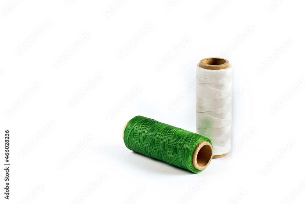 A skein of white and green thread. Coils of colored threads on a white background. Waxed sewing thread for leather goods. A skein of white and green thread. Coils of colored threads on a white background. Waxed sewing thread for leather goods.