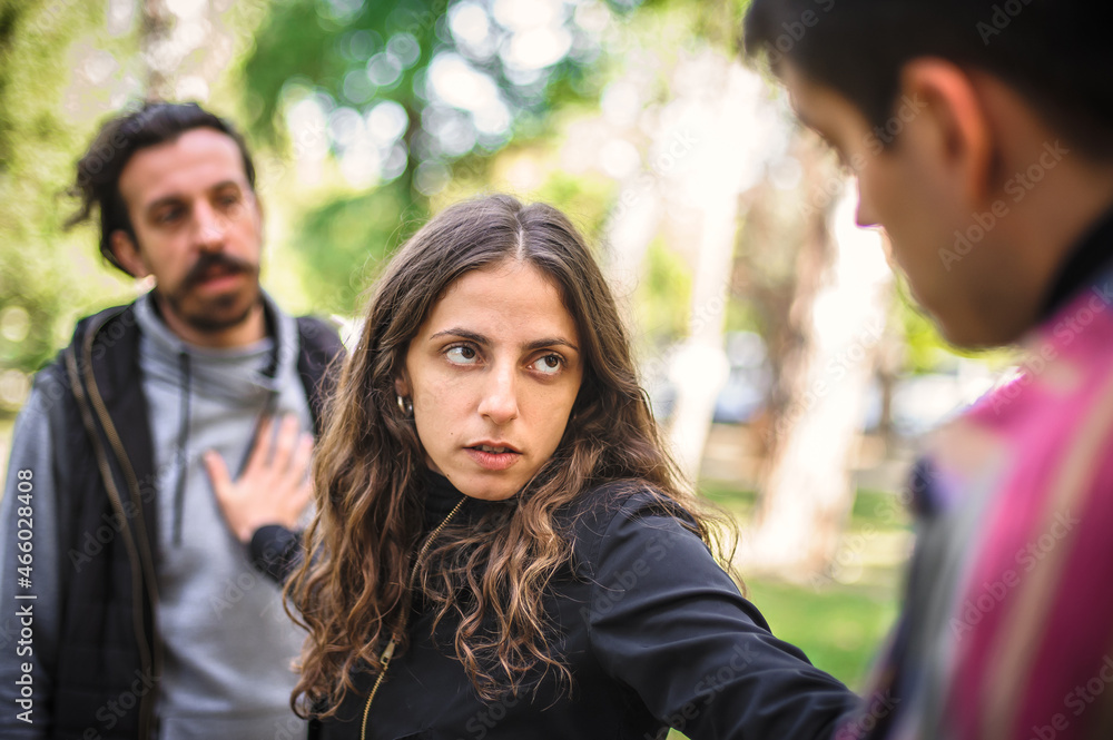 Fototapeta premium Woman with outstretched arms tries to separate men in quarrel