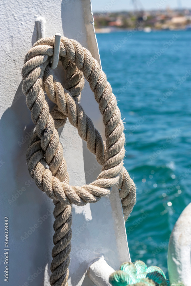 Rope is tied with sea knot and hangs on board ship. Vertical. Topic - sea adventures, sea voyages. Vacation at sea