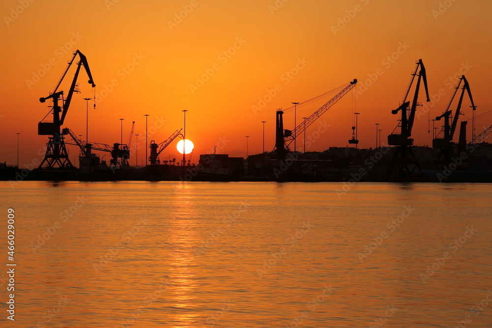 cranes in port at sunrise