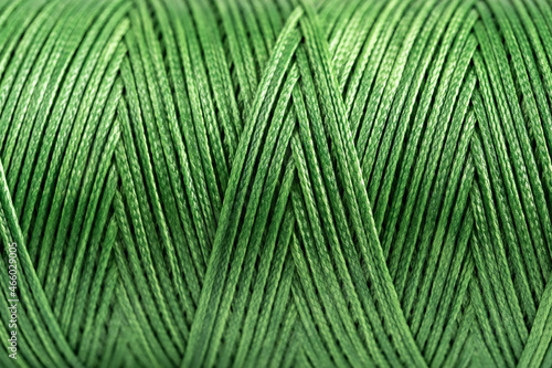 A coil of green thread. Spool of colored threads on a white background. Waxed sewing thread for leather crafts.
