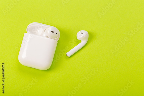 white wireless headphones with charging case on green background