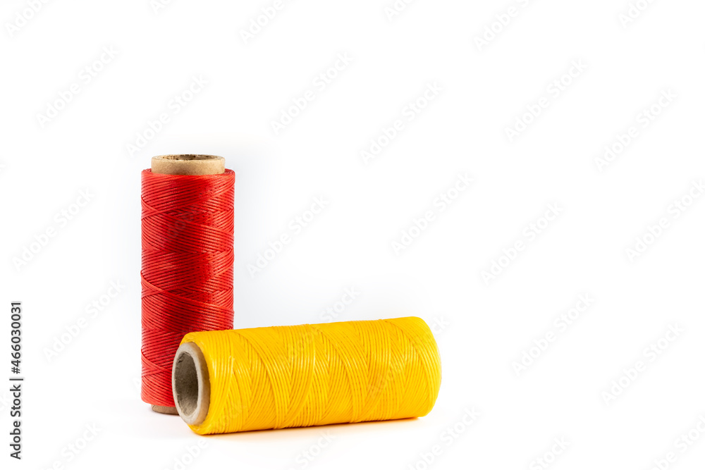 A skein of yellow and red thread. Coils of colored threads on a white background. Waxed sewing thread for leather goods.