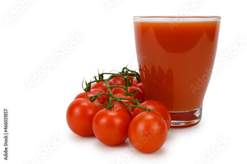 Side view of a glass of tomato juice and a bunch of bush tomatoes