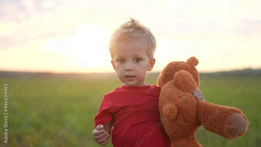 portrait of a baby boy with a toy teddy bear in his hands on nature in ...