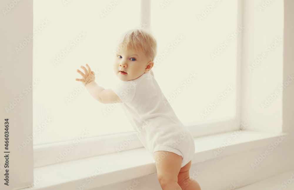 little baby touching window in white room at home little baby touching window in white room at home