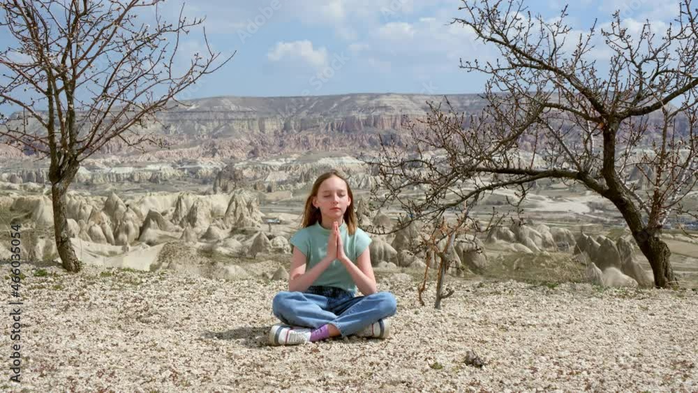 Young woman practising outdoor lotus pose in highlands valley. Yoga woman relaxing in lotus asana with praying palm hands Young woman practising outdoor lotus pose in highlands valley. Yoga woman relaxing in lotus asana with praying palm hands
