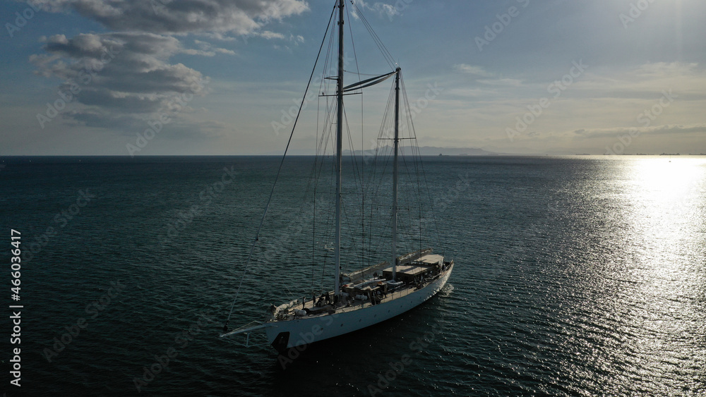 Aerial photo of luxury yacht - sail boat anchored in deep blue waters of Santorini island, Cyclades, Aegean, Greece