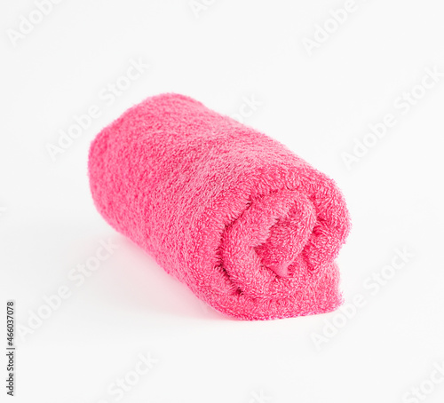 Pink terry towel rolled up on a light background.