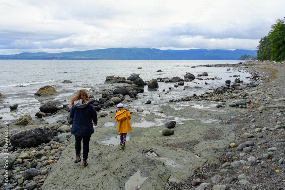 A mother and daughter exploring the shores near the famous balance rock on the east coast of Graham Island, outside Skidegate, Haida Gwaii, British Columbia, Canada