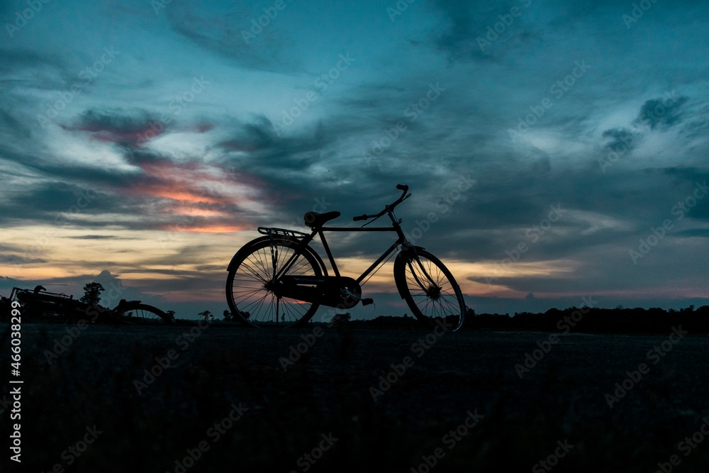 Bi-Cycle silhouette in front of sunset cloudy landscape Bi-Cycle silhouette in front of sunset cloudy landscape