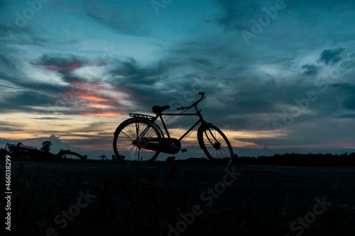 Bi-Cycle silhouette in front of sunset cloudy landscape