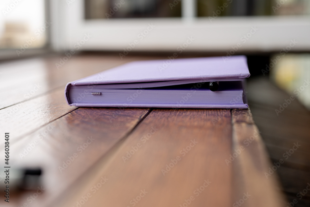 purple creative diary for writing with pencils and a capillary pen lies on a wooden table. concept is planning and writing in a notebook.