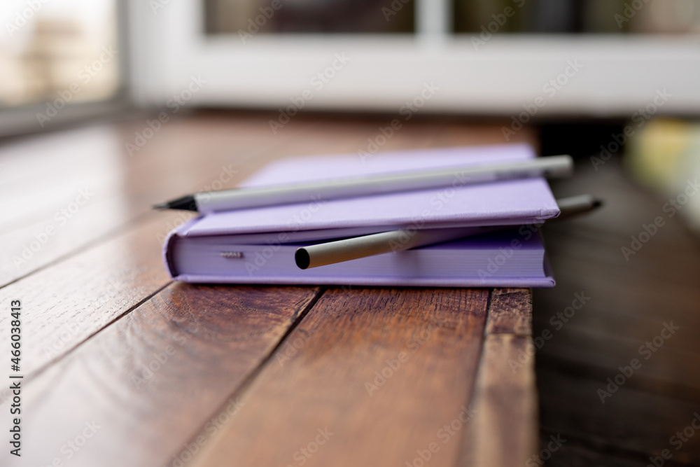 purple creative diary for writing with pencils and a capillary pen lies on a wooden table. concept is planning and writing in a notebook. purple creative diary for writing with pencils and a capillary pen lies on a wooden table. concept is planning and writing in a notebook.