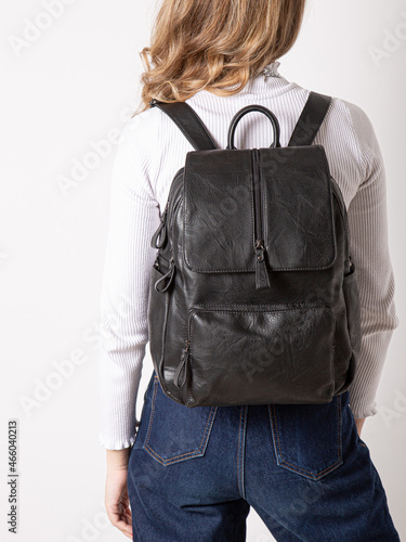 black backpack bag with straps on girl's back. bag for things, accessories and textbooks. Leather backpack with locks.