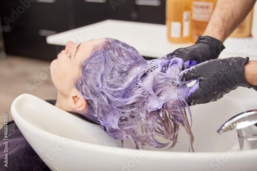 Hairdresser hands applying toning shampoo on woman hair